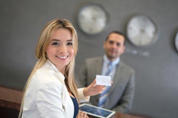 Beruf Hoteltester Frau an Hotelrezeption mit Rezeptionist im Hintergrund