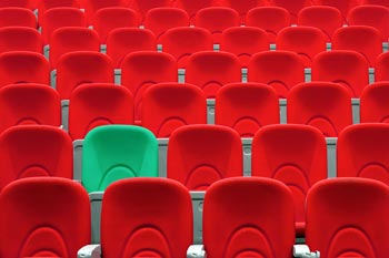 Vorlesungssaal mit roten Sesseln und einem grünen Sessel